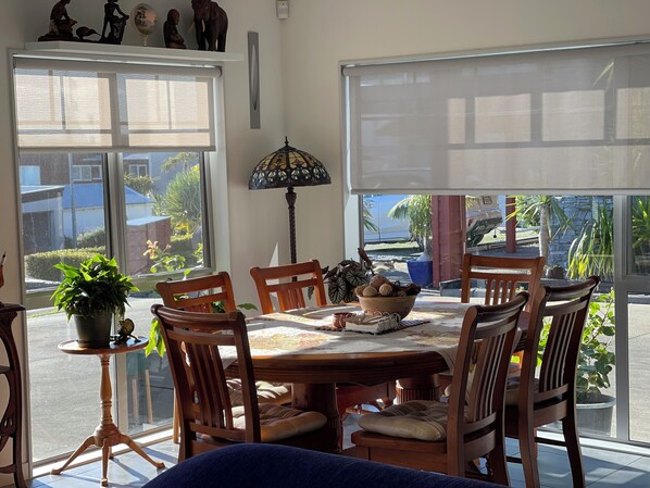 A dining area with a round table, wooden chairs, a potted plant, and a lamp. - Langs Beach Luxury Apartment (Langs Beach)