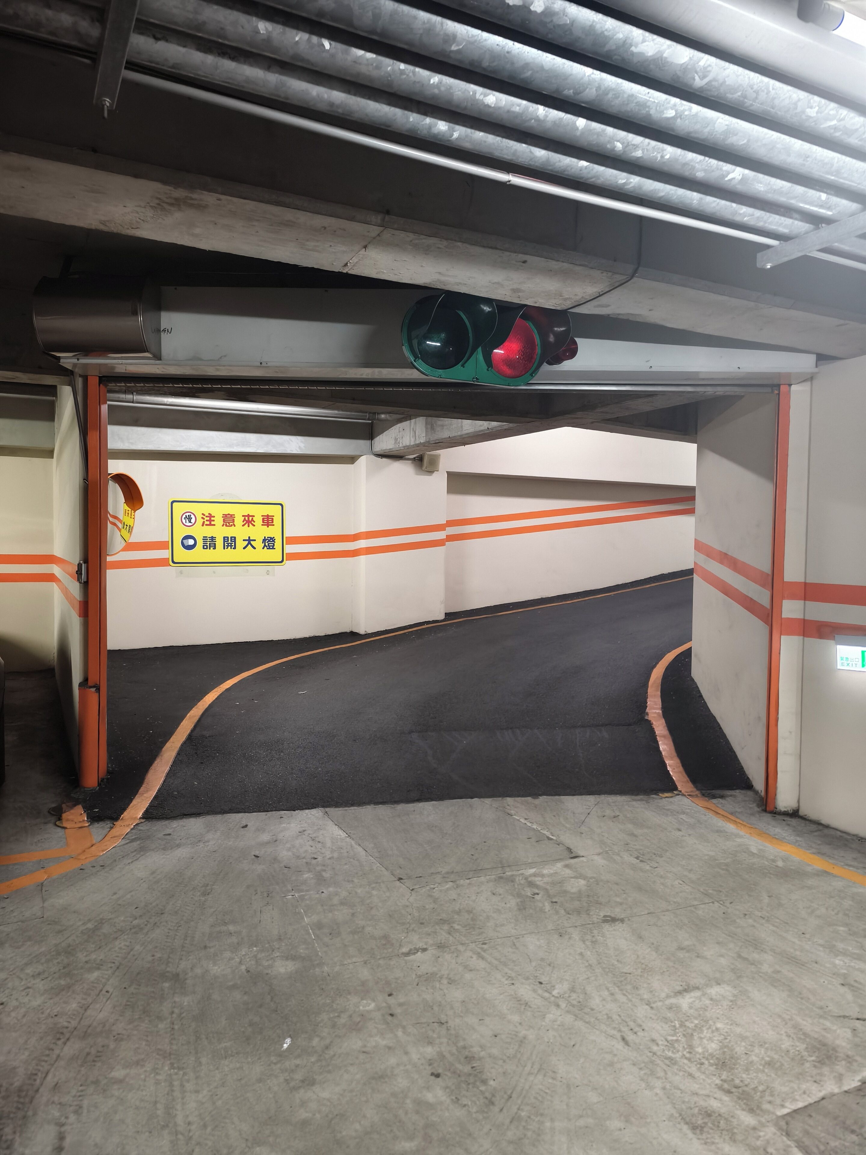A parking garage with a traffic light, orange lines on the floor, and a sign with Chinese characters.