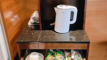 Minibar de una habitación de hotel con cafetera, botellas de agua, vasos y sobres de té.
