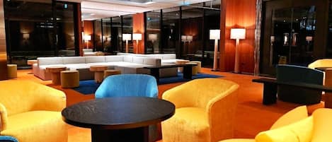 Un vestíbulo moderno con una zona de estar que incluye sofás, sillones, una mesa de centro y un ventanal con vistas a la ciudad.