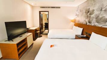 A hotel room with a bed, a TV, a desk, and a bathroom visible through an open door.
