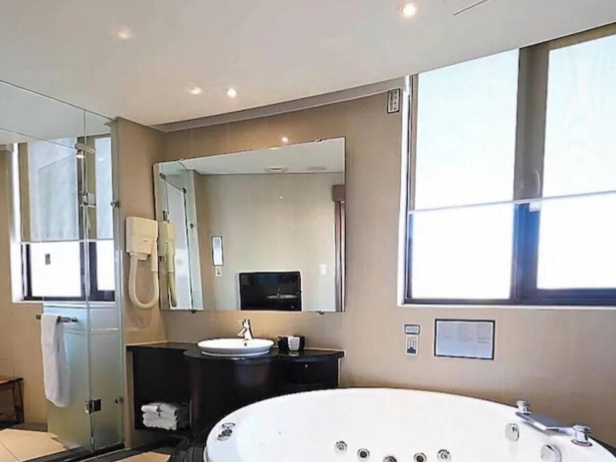 Un baño moderno con una bañera grande, una cabina de ducha de vidrio y un lavamanos con espejo.