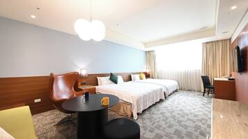 Quarto de hotel com cama, escrivaninha, cadeira, mesa de centro e luminária de teto singular.