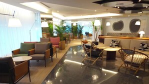 Un vestíbul d'hotel modern amb diverses opcions d'asseients, com ara sofàs, cadires i una zona de bar.