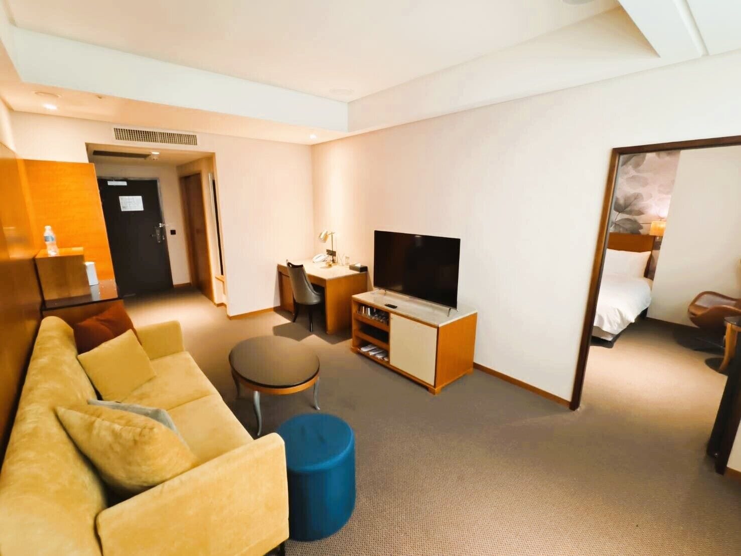 A hotel room with a sofa, a television, a desk, and a bed.