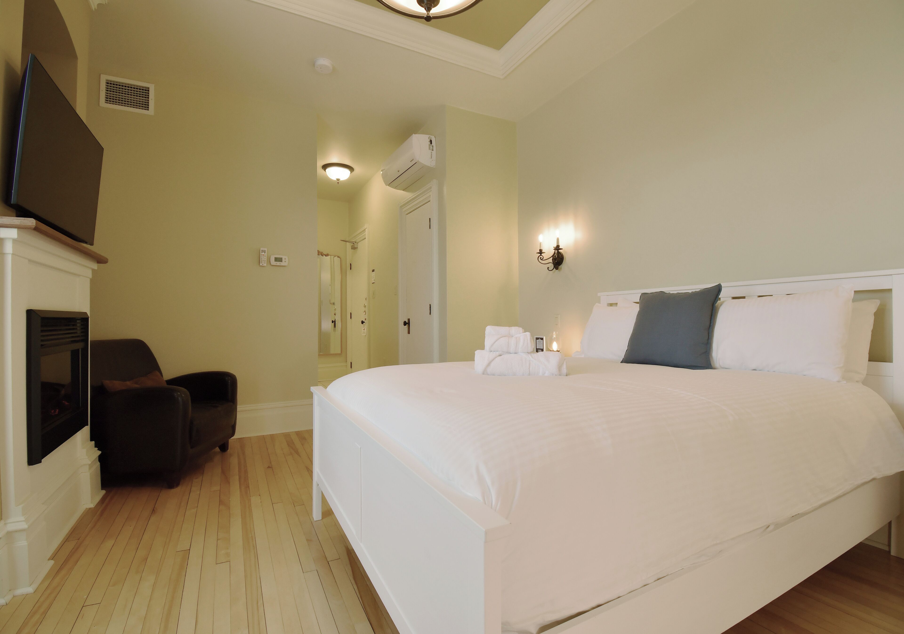 Een slaapkamer met een groot bed, een stoel, een televisie en een open haard.
