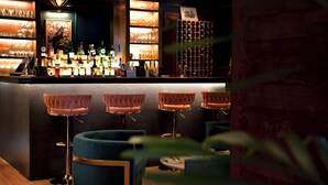 Zona de bar con mostrador, taburetes y una estantería para vinos.