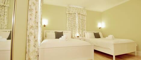 A hotel room with two beds, a mirror, and a ceiling light.
