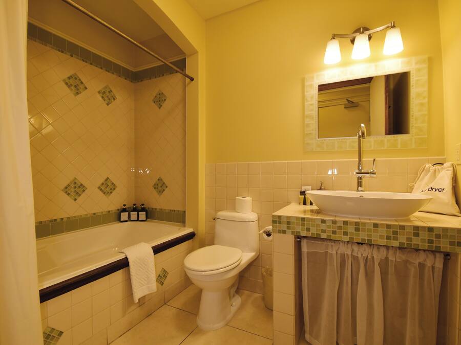 Un baño con bañera, inodoro, lavamanos y ducha.