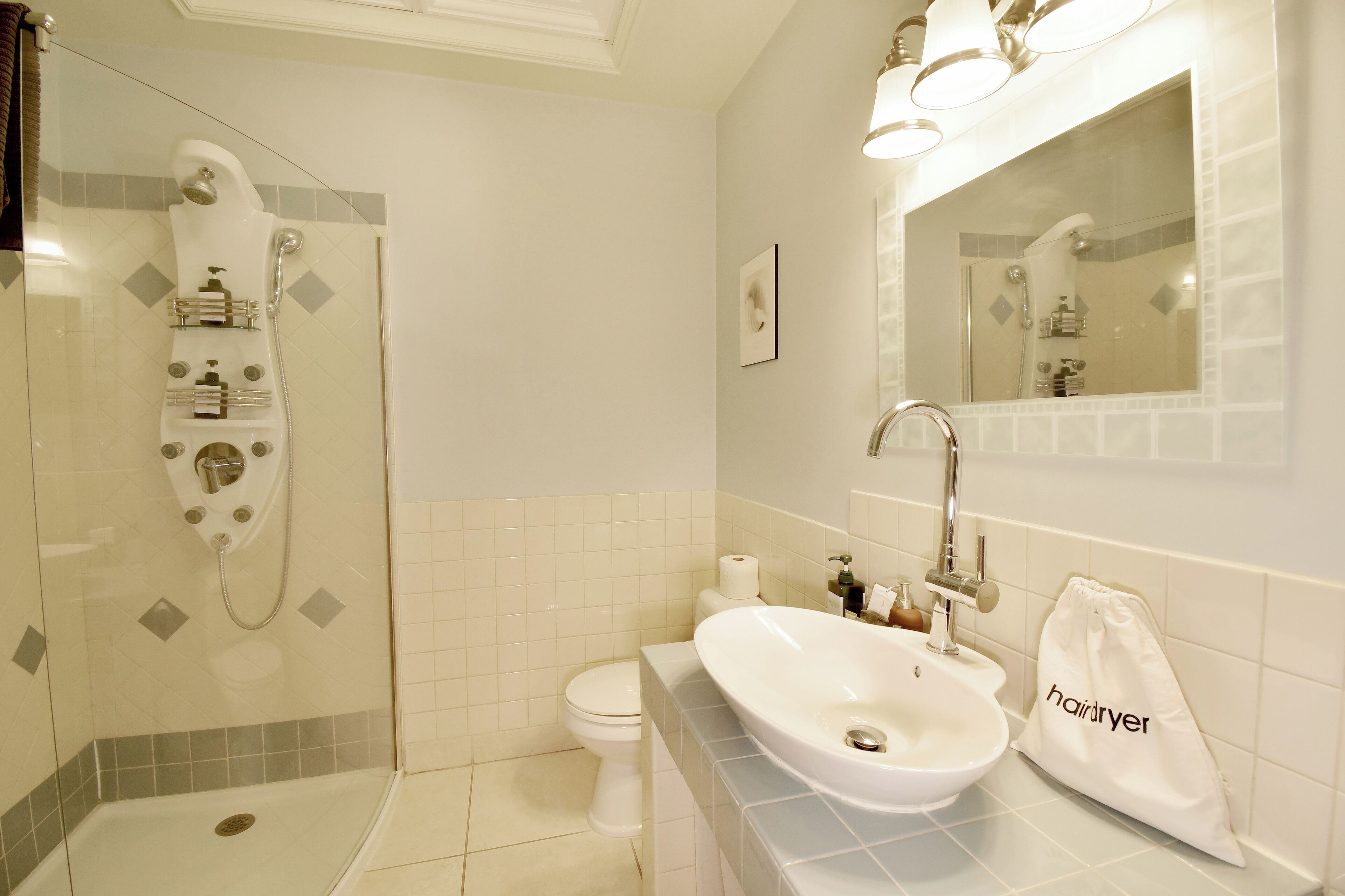 Une salle de bain avec une douche à parois de verre, un lavabo blanc et un miroir au-dessus du lavabo.