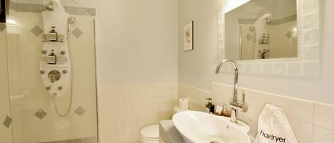 Une salle de bain avec une douche à parois de verre, un lavabo blanc et un miroir au-dessus du lavabo.