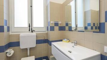 Ein Badezimmer mit Toilette, Waschbecken und Spiegel.