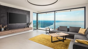 A modern living room with a large flat-screen TV, a wooden coffee table, a gray sofa, and a yellow rug. - Opatija Sky by Interhome (Opatija/Bregi)