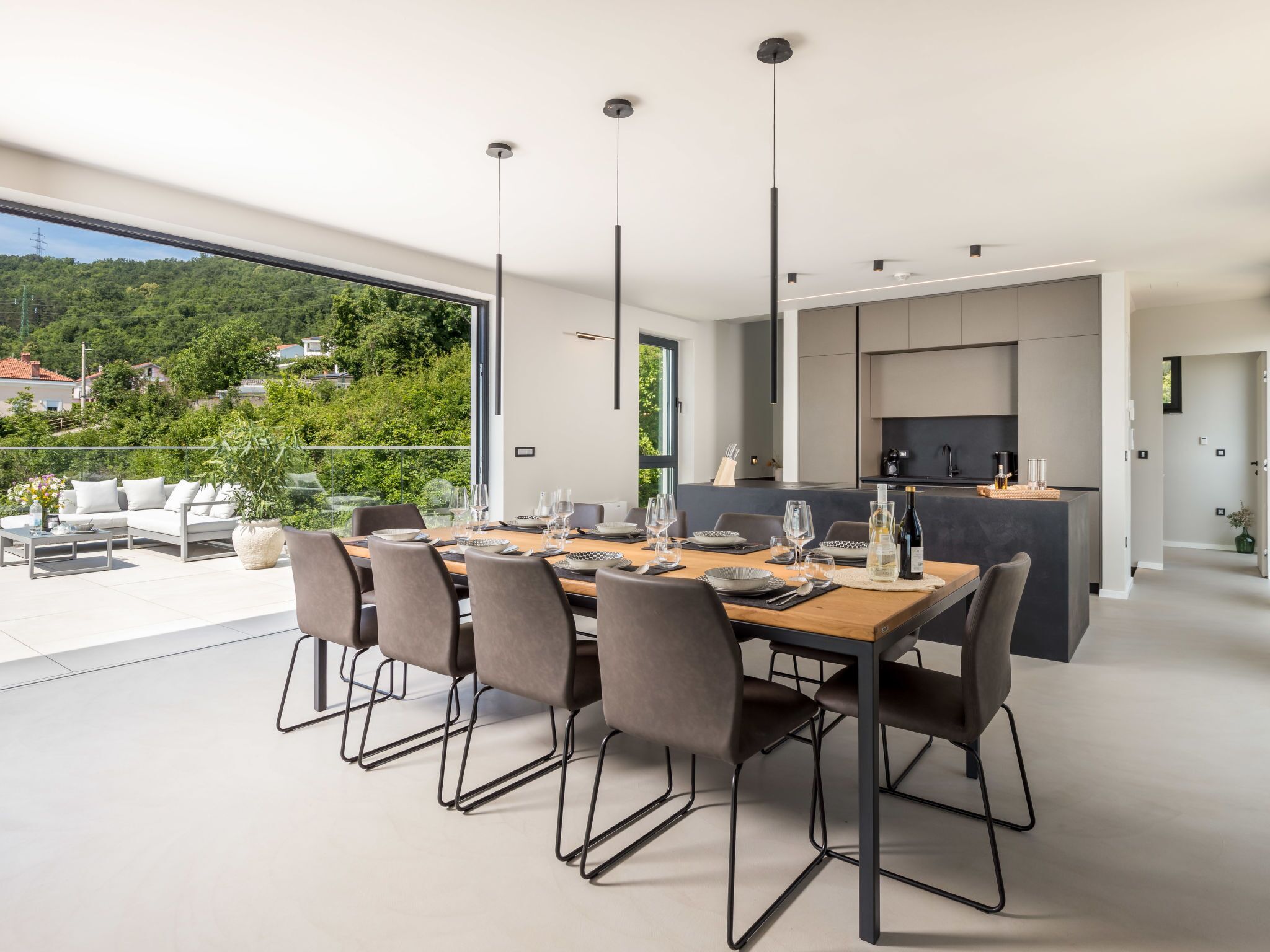 A modern dining area with a large table set for six, surrounded by chairs.