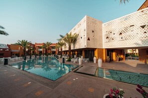 A hotel courtyard with a swimming pool, palm trees, and outdoor seating areas. - Vivienda Hotel Villas Diplomatic Quarter (Riyadh)