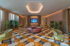 A lobby with a checkered floor, a central seating area, and a television screen. - Vivienda Hotel Villas Diplomatic Quarter (Riyadh)