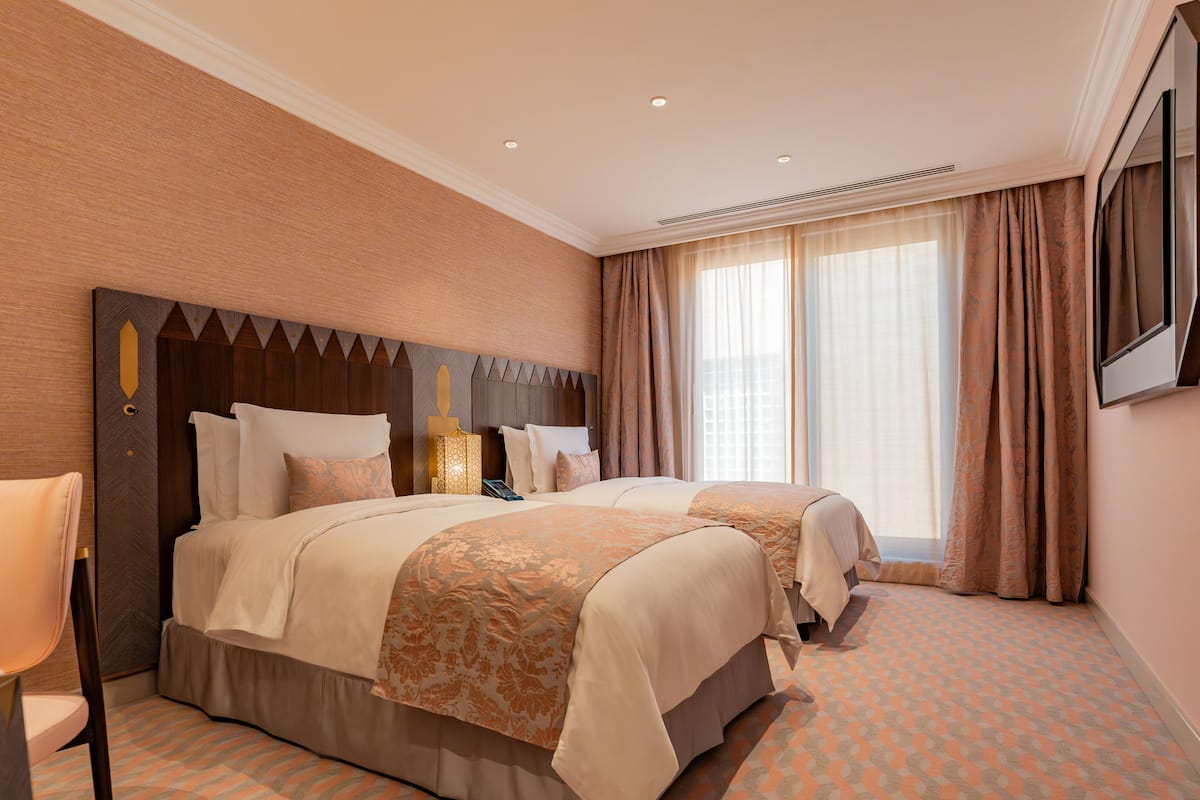 A hotel room with two beds, a large mirror, and a view of the city.