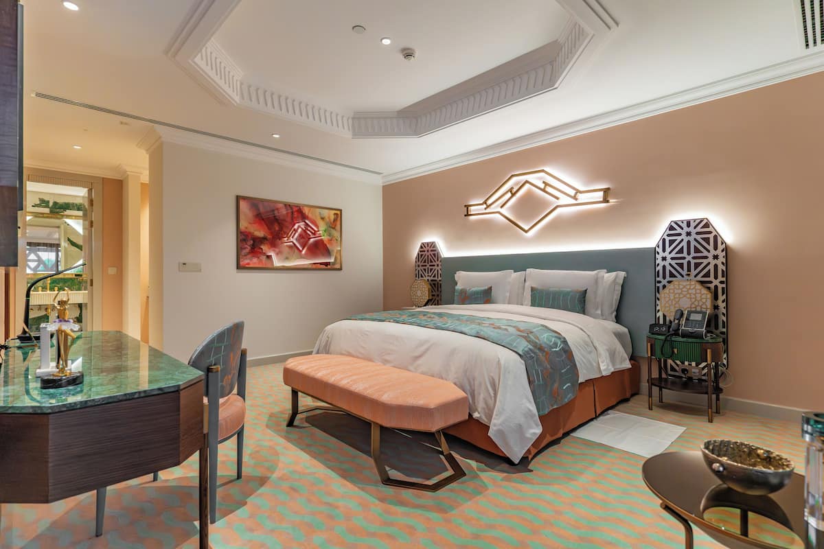 A modern bedroom with a large bed, a desk, and a bench.