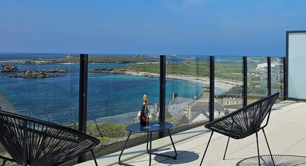 Un balcon avec une table et des chaises donnant sur une vue panoramique de la côte.