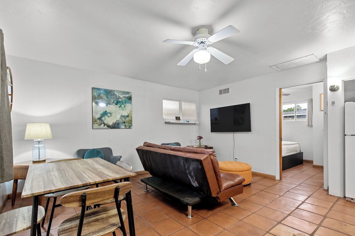 A compact living space with a dining area, a sofa, a TV, and a ceiling fan.