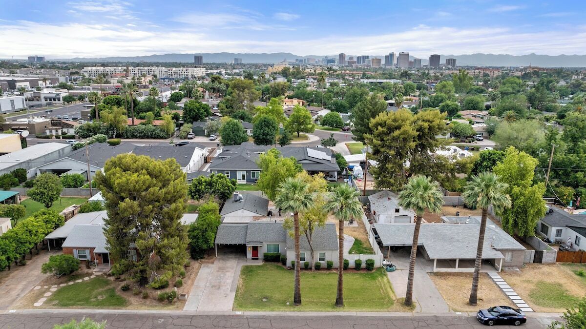 A residential area with houses, trees, and a distant city skyline.