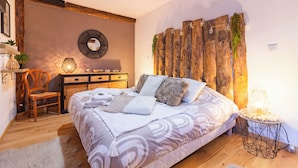 A bedroom with a large bed, a wooden headboard, a side table with a lamp, a chair, and a dresser. - Le Gîte Spa du Cèdre Bleu Absolute Place of Relaxation and Soothing!  (La Tourette-Cabardès)