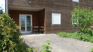 A wooden building with a covered porch, a sliding glass door, and a small table with chairs. - 18moliereFr 5 pers. sheets, towels & cleaning included (Chasseneuil-du-Poitou)