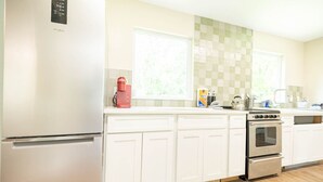 A modern kitchen with white cabinets, a stainless steel refrigerator, a double oven, and a coffee maker on the counter. - Historic Oviedo Charmer - Close to everything (Oviedo)