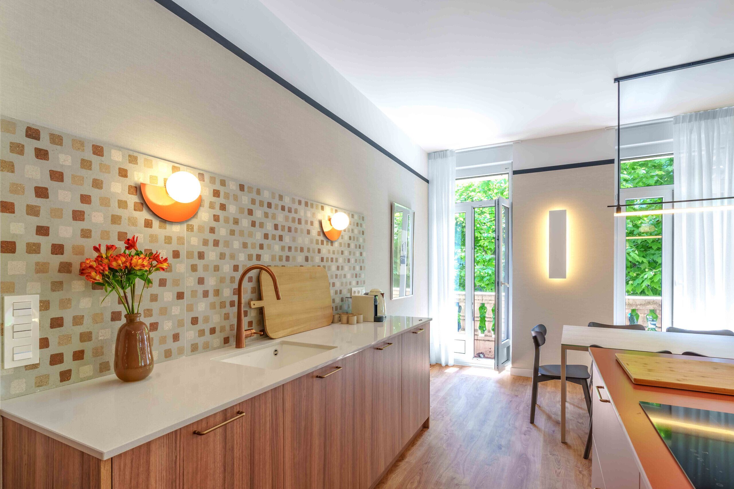 Una cucina moderna con una grande isola, un vaso di fiori e un tagliere di legno.