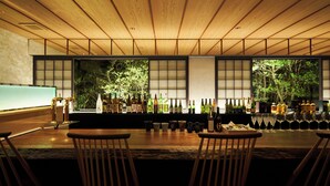 A bar area with wooden chairs, a long counter, and various bottles and glasses. - Villa Ryusei (Shima)