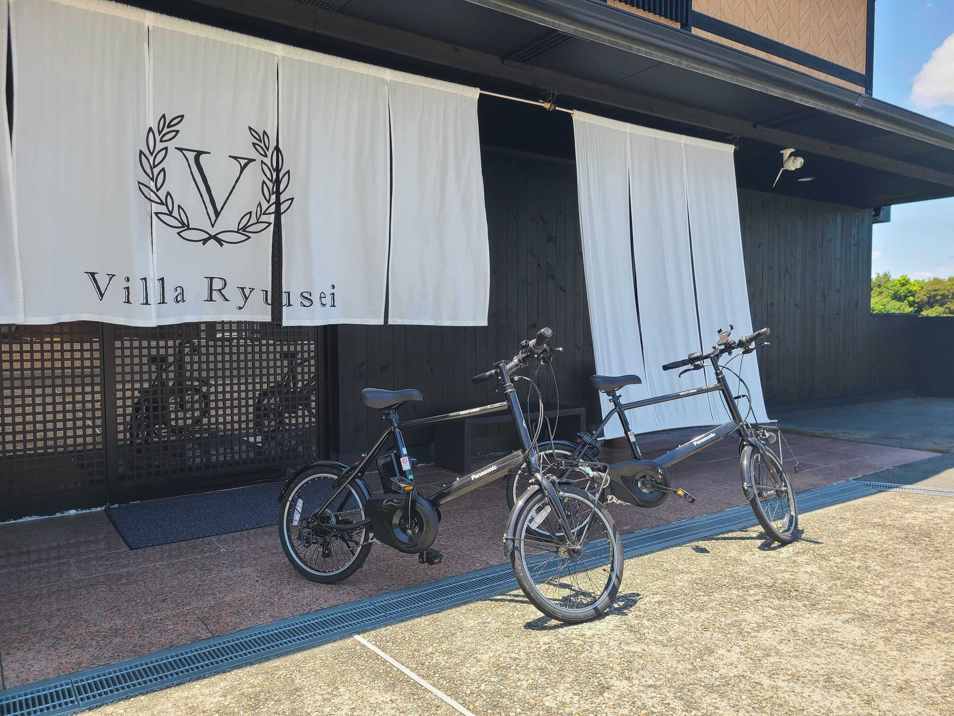 Un edificio con un cartel que dice "Villa Ryusei" y dos bicicletas estacionadas afuera.