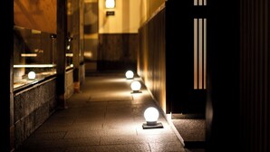 A corridor with a series of illuminated globes on the floor, leading to a door with vertical stripes. - Villa Ryusei (Shima)