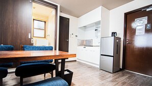 Una cocina moderna con una mesa de comedor de madera, sillas tapizadas en azul, un refrigerador de acero inoxidable y armarios blancos.