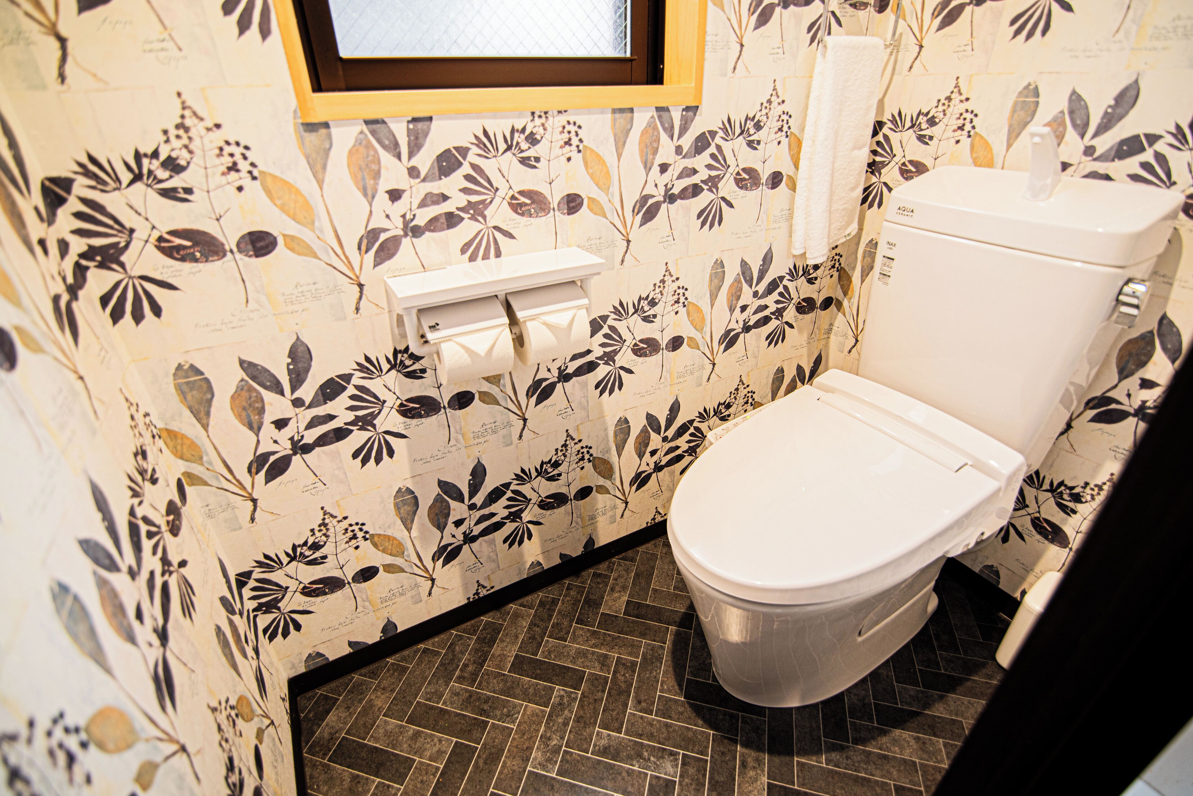 A bathroom with a toilet, a hand dryer, and a wall-mounted paper towel dispenser.