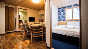 Habitación de hotel con techo de madera, cama con sábanas blancas, escritorio con silla y pared azul con ventana.