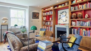 Un salon chaleureux avec une cheminée, des étagères à livres et des fauteuils confortables.