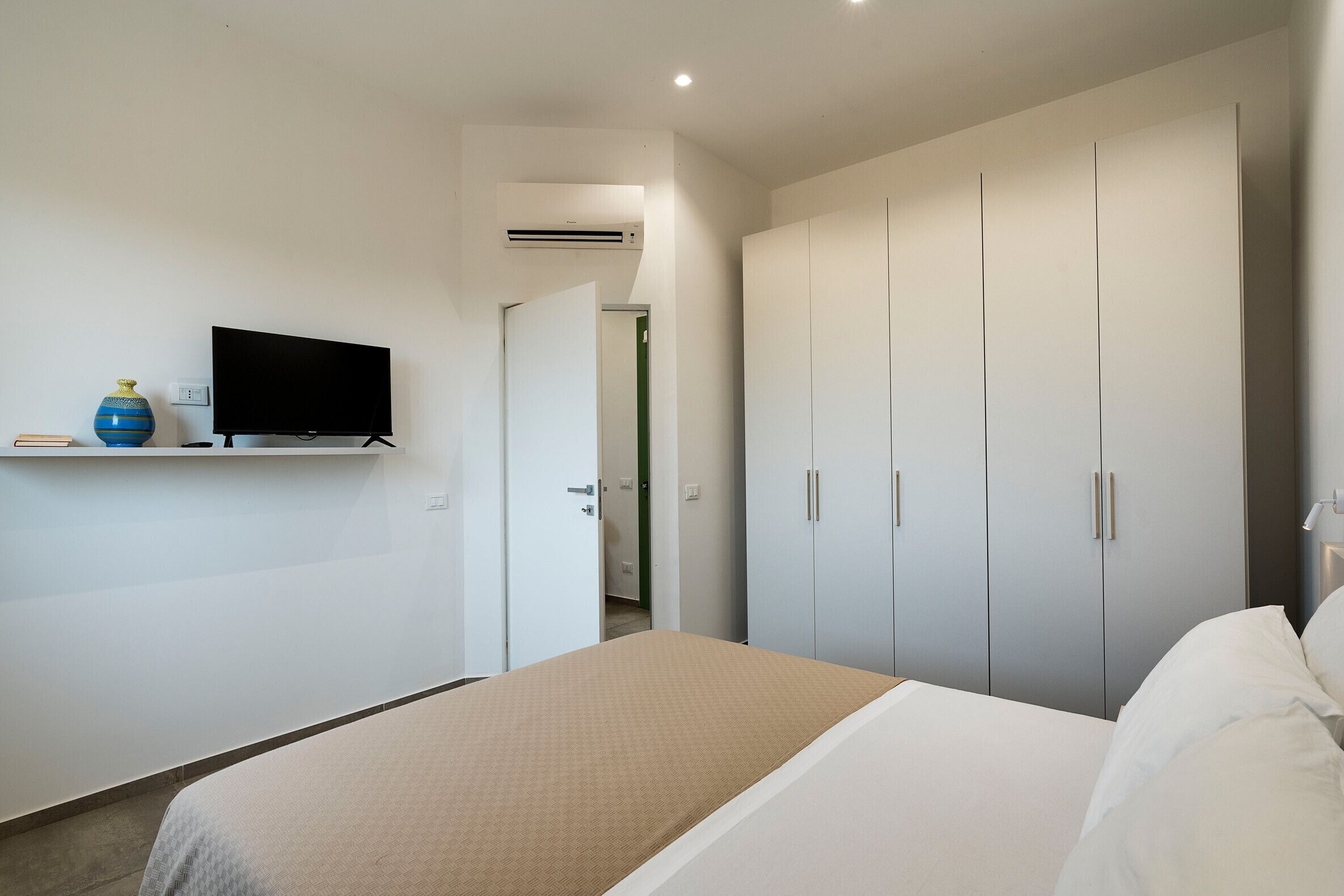 Una camera da letto con un letto, una televisione su uno scaffale e un armadio.