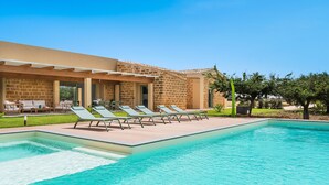 A swimming pool with lounge chairs and a building with stone walls. - Beautiful villa with pool in Menfi (Menfi)