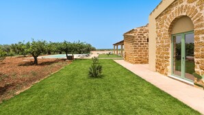 A well-maintained lawn with a stone building featuring a glass door and a clear view of the surrounding landscape. - Beautiful villa with pool in Menfi (Menfi)