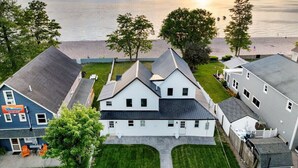 A coastal residential area with houses, a beach, and a sunset. - Parks  Slice Heaven | 2BR Waterfront| with Hot tub (Sylvan Beach)