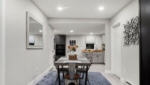 A modern kitchen with white cabinets, a black countertop, and a decorative wall art piece. - Parks  Slice Heaven | 2BR Waterfront| with Hot tub (Sylvan Beach)