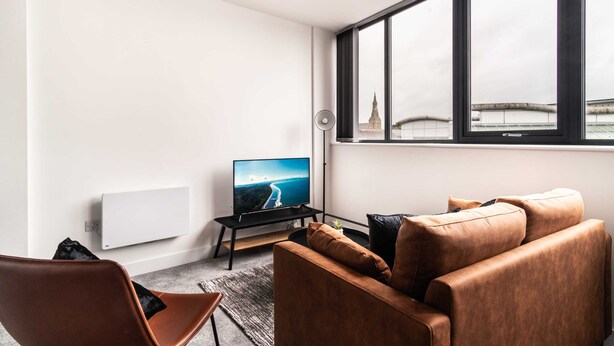 Una sala de estar moderna con un ventanal grande, un televisor de pantalla plana, un sofá y una silla.