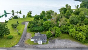 A house with a driveway leading to a dock, surrounded by lush greenery and a large body of water. - "Whitewater-The Genoa" on Oneida Lake/Sleeps 8! (Canastota)