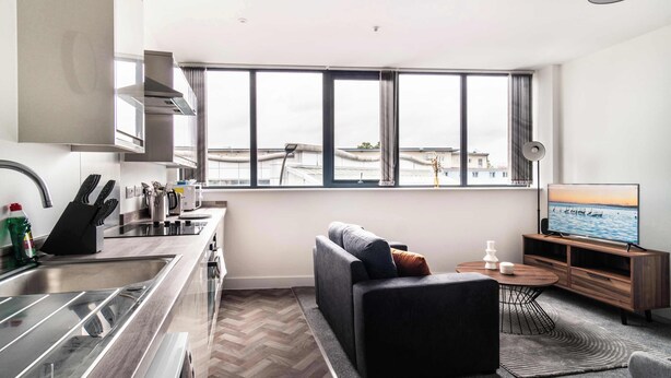 A modern kitchen with a large window, a sofa, a TV, and a dining area. - Fabulous 1 BED Apartment Central Wrexham with WiFi (Wrexham)