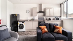 A modern kitchen with a washing machine, microwave, and cabinets. - Fabulous 1 BED Apartment Central Wrexham with WiFi (Wrexham)