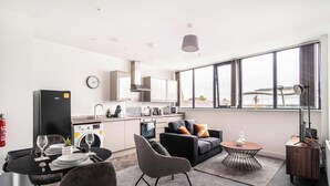 A modern living room with a dining area, a sofa, a coffee table, and a kitchen in the background. - Fabulous 1 BED Apartment Central Wrexham with WiFi (Wrexham)