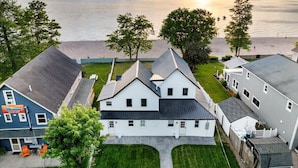 A coastal residential area with houses, a beach, and a sunset. - Park Peaks on the Beach| 4BR Waterfront | Hot tub | Sleeps 12! (Sylvan Beach)