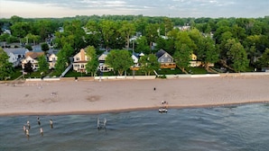 A beach with houses in the background and people swimming in the water. - Park Peaks on the Beach| 4BR Waterfront | Hot tub | Sleeps 12! (Sylvan Beach)