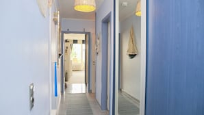 Un couloir aux murs bleus, doté d’un sol à motifs et agrémenté d’une décoration en forme de voile suspendu.