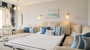 Une chambre d’hôtel avec un grand lit, deux tables de chevet, une chaise et un tableau au mur.
